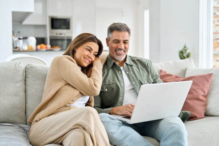 Happy,Middle,Aged,Couple,Using,Laptop,Relaxing,On,Couch,At